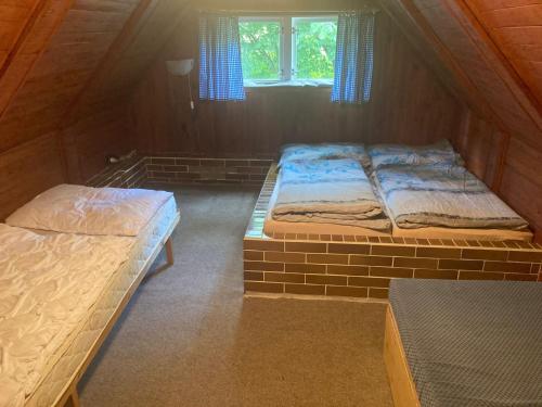 2 Betten in einem kleinen Zimmer mit Fenster in der Unterkunft Chaloupka in Žacléř