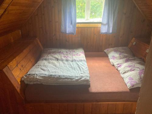 ein leeres Bett in einer Holzhütte mit Fenster in der Unterkunft Chaloupka in Žacléř