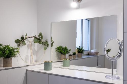 a white bathroom with a mirror and potted plants at Sunnybelle Appartements Dresden I in Dresden