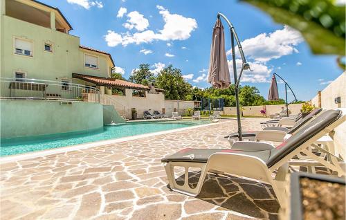 uma piscina com cadeiras e um guarda-sol ao lado de uma casa em Amazing Apartment In Pula With Outdoor Swimming Pool em Pula