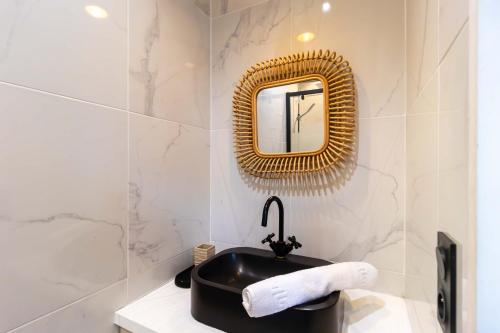 une salle de bain avec un lavabo noir et un miroir dans l'établissement Apartment Center of Paris by Studio prestige, à Paris