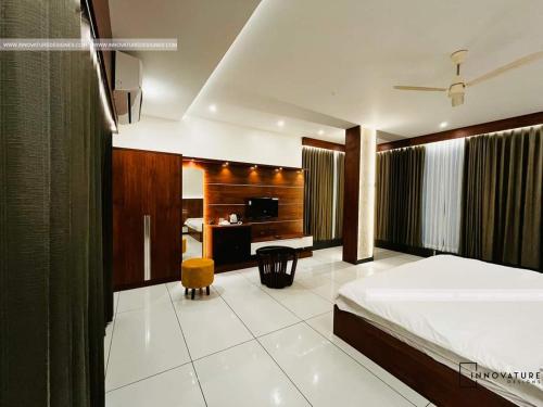 hotel 24inn residency في Pathanāmthitta: غرفة نوم بسرير ومكتب وتلفزيون