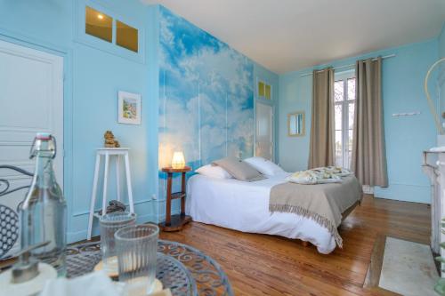 um quarto com paredes azuis e uma cama com lençóis brancos em Château de la villeneuve em Saint-Marcel