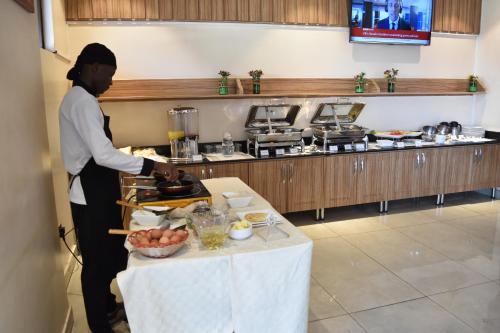 a man standing in a kitchen preparing food at Millennium Terrace Hotel in Kampala