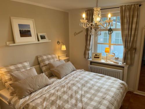 a bedroom with a bed and a window and a chandelier at Deichhof Whg 23 in Dunsum