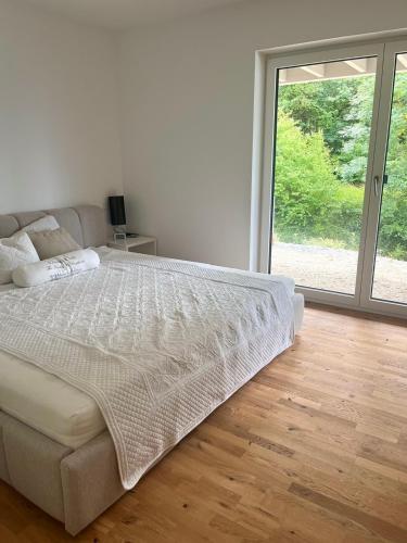 a white bedroom with a bed and a large window at Wohnung am Wald in Geisa