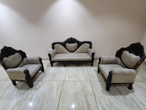 three chairs and a couch in a room with a wall at Holiday Home in Ujjain