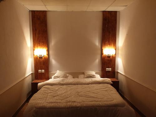 łóżko w pokoju z dwoma światłami na ścianie w obiekcie شاليه مزدانة w Mekce