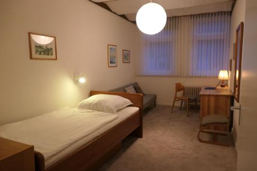 ein Schlafzimmer mit einem Bett, einem Stuhl und einem Tisch in der Unterkunft Malerhaus Einbeck in Einbeck