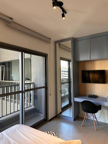 a bedroom with a bed and a desk with a balcony at Estúdio VN Consolação in Sao Paulo