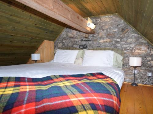 1 dormitorio con 1 cama en una pared de piedra en 1 Bed in Loch Ness I662C, en Invermoriston
