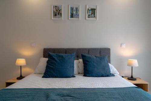 1 dormitorio con 1 cama con almohadas azules y 2 lámparas en Modern apartment with balcony and free parking en Oporto