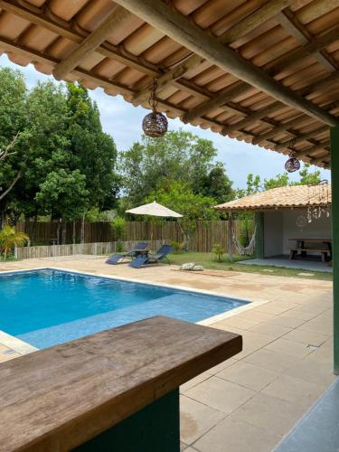 a swimming pool with a wooden pergola and a swimming pool at Casa Lua Cheia in Praia do Espelho