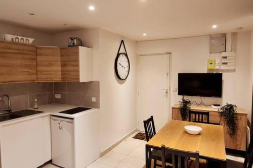 une cuisine avec une table et une horloge au mur dans l'établissement Appart cosy et fonctionnel, quartier très sympa, à Paris