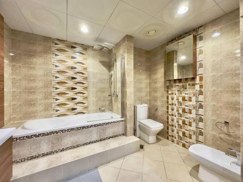 a bathroom with a tub and a toilet and a sink at AR Holiday Home JBR 2 in Dubai