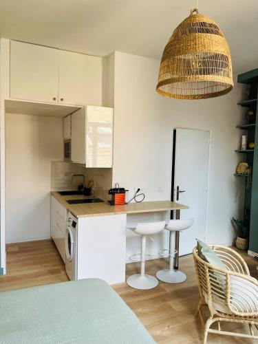 une cuisine avec des armoires blanches et une table et des chaises dans l'établissement Logement forte proximité Gares de Lille, à Lille