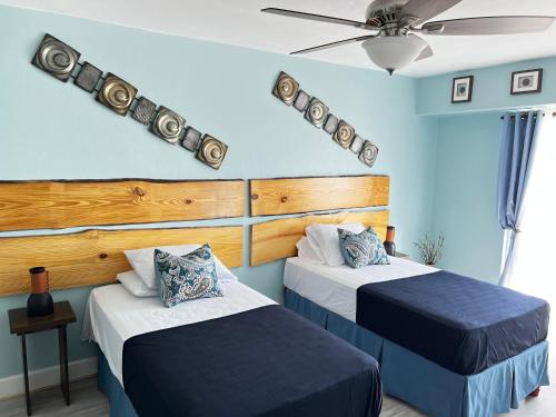 1 dormitorio con 2 camas y ventilador de techo en SEAFLECTIONS, en Kingston