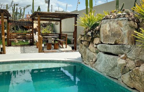 a swimming pool with a stone wall next to a stone at Volantes do Sertão - Ecoville in Piranhas