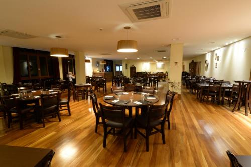 a restaurant with wooden floors and tables and chairs at Vista Azul Apart Hotel - Vista Pinheiros in Domingos Martins