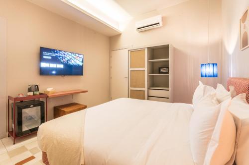 a bedroom with a white bed and a tv on the wall at JEMAA EL FNA Suites & Spa in Marrakech