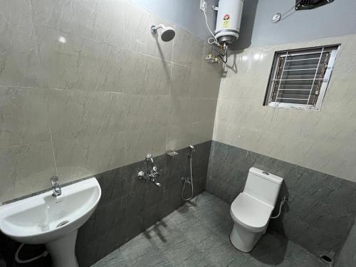 a bathroom with a white toilet and a sink at Urban Suites Silpukhuri in Guwahati