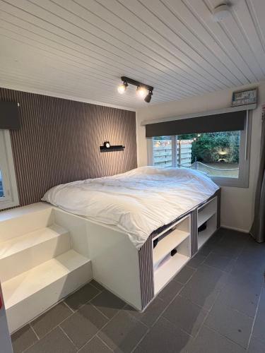 ein weißes Bett in einem Zimmer mit Fenster in der Unterkunft The Zen Nest in Geel