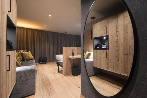 DOLOMITI EXCLUSIVE YOUR MOUNTAIN SUITE في بوتسا دي فاسّا: مرآة في غرفة الفندق مع غرفة نوم