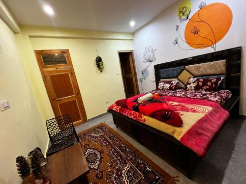 a bedroom with a bed with a red comforter at Karma Guest House and Cafe in Kalgha