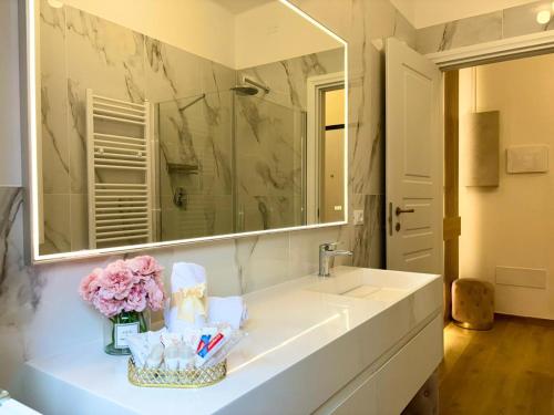 a bathroom with a sink with a mirror and flowers at Sant'Orsola Lodge Bologna in Bologna