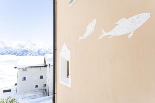 two fish stencils on a wall next to a window at Chasa Fabulusa in Ftan