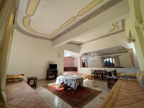 Tiguimi Vacances - Oasis Villas, cadre naturel et vue montagne في أغادير: غرفة معيشة كبيرة مع طاولة وكراسي