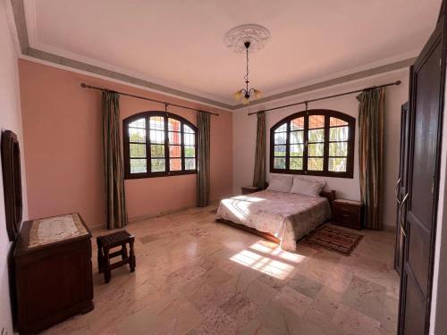 ein Schlafzimmer mit einem Bett und zwei Fenstern in der Unterkunft Tiguimi Vacances - Oasis Villas, cadre naturel et vue montagne in Agadir