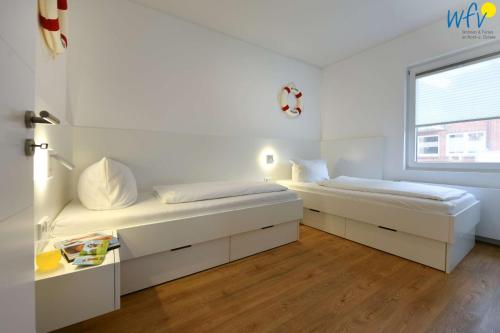 ein weißes Schlafzimmer mit 2 Betten und einem Fenster in der Unterkunft Bungalow Hasela mit Workation Juist in Juist
