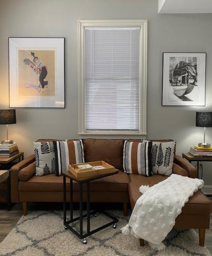 a living room with a brown couch and a window at 2 BR Loft - Walk to Cafes-Breweries- Arts & Entertainment District in Glens Falls