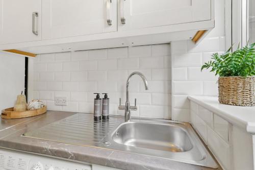 a stainless steel sink in a kitchen with white cabinets at Wembley Hububb Stay in London