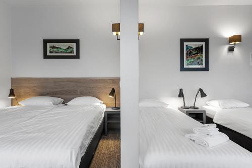 two beds in a hotel room with white sheets at Hotel Vellir in Hafnarfjördur