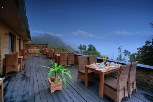 a wooden deck with tables and chairs on a balcony at Sarangkot Mountain Lodge in Pokhara
