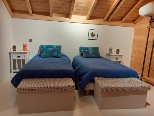 a room with two beds with blue covers and benches at Charmant chalet 8p calme et vue sur montagnes in Verchères