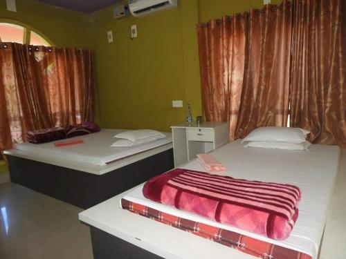 a room with two beds and a window with curtains at Prakriti neerh in Jyoti Gaon