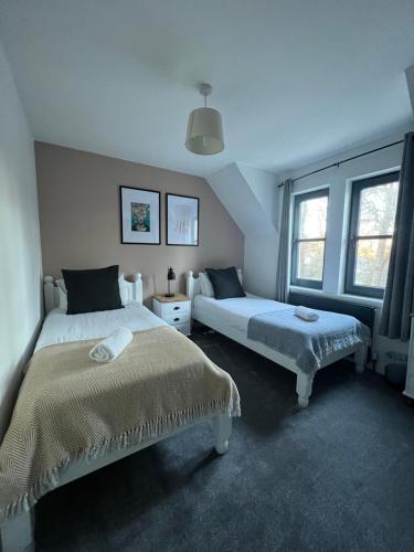 een slaapkamer met twee bedden en twee ramen bij Nevis Croft Apartment 2 in Fort William