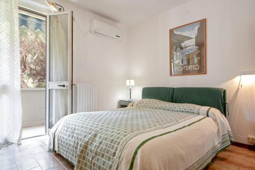 1 dormitorio con 1 cama con cabecero verde y ventana en Cozy Apartment 2minutes from the beach, en Cecina