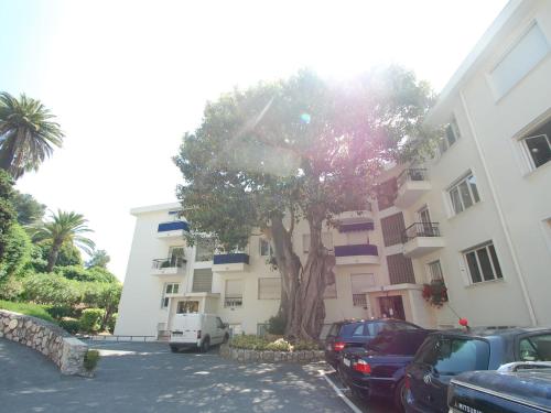 un bâtiment avec des voitures garées devant un arbre dans l'établissement Studio plaisant avec grande terrasse ensoleillée près du centre et des plages - FR-1-196-319, à Menton