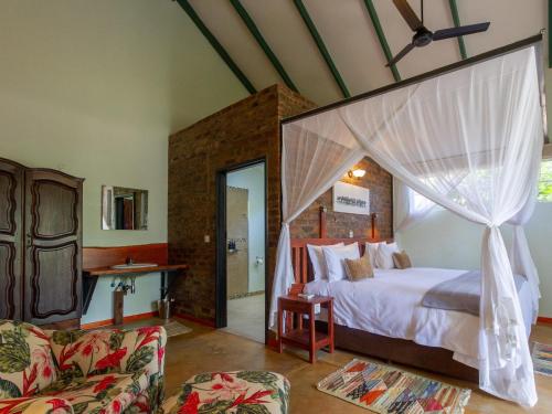 1 dormitorio con 1 cama con dosel en The Courtney Lodge en Victoria Falls