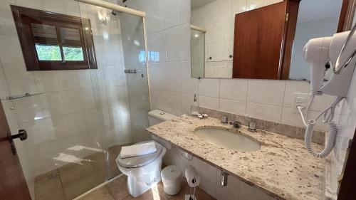 ein Badezimmer mit einem Waschbecken, einem WC und einem Spiegel in der Unterkunft Pousada Flor de Lua Monte Verde in Monte Verde