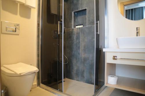 a bathroom with a shower with a toilet and a sink at Güllük Uno Elegance Otel in Gulluk