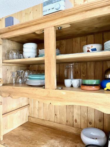 une étagère en bois avec des assiettes, des bols et de la vaisselle dans l'établissement Appartement T1 pour 5 aux 2 Alpes - Terrasse sur jardin, Wi-Fi, parking gratuit, à Les Deux Alpes
