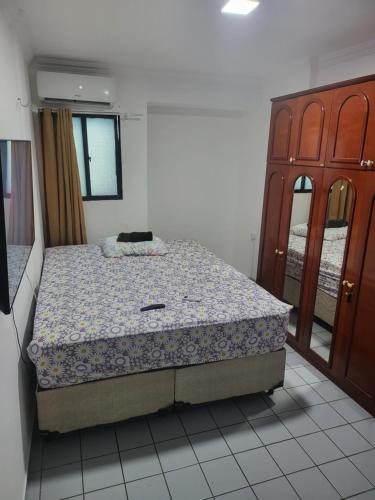 a bedroom with a bed and a wooden cabinet at Apartamento 3 quartos beira mar Intermares-Cabedelo VALOR DA TAXA DE LIMPEZA E DO AR CONDICIONADO COBRADO À PARTE in Cabedelo