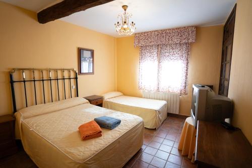 a bedroom with two beds and a tv and a tv at Casa Rural Los Arrieros in La Puerta