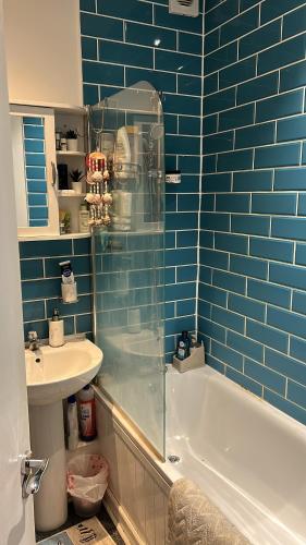 een blauw betegelde badkamer met een bad en een wastafel bij Quite and peaceful room in Londen
