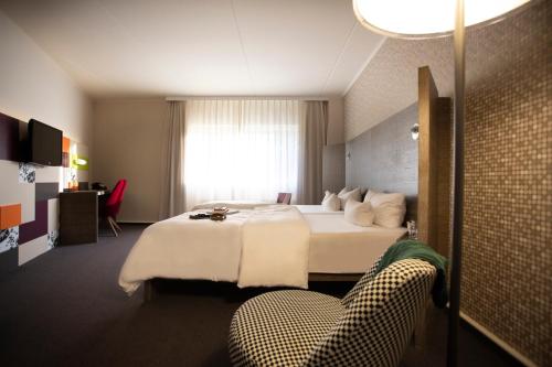 una camera d'albergo con letto e sedia di Pentahotel Leipzig a Lipsia